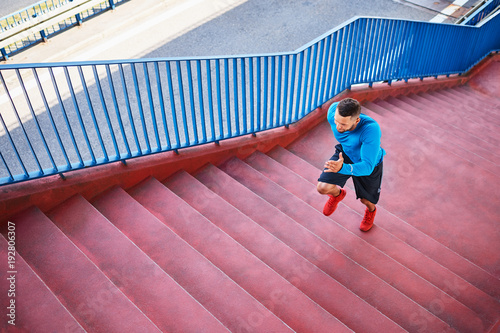 Top view of an athletic man running on stairs during an outdoors workout in the city