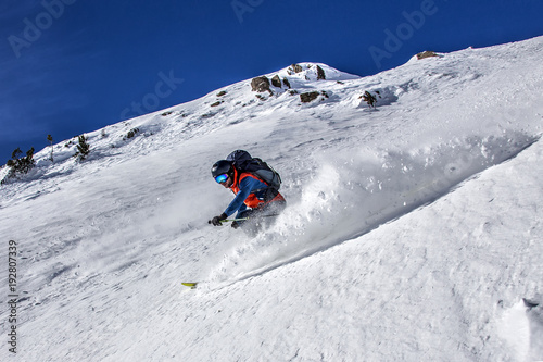 Expert skier skiing down through steep terrain