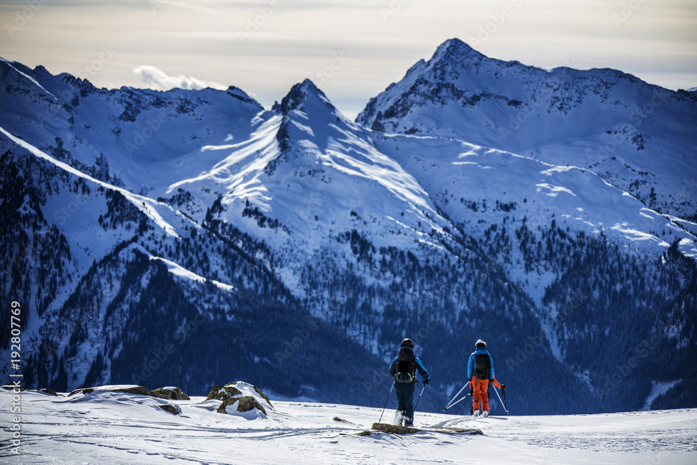 Two back country skiers looking forward at the steep mountain
