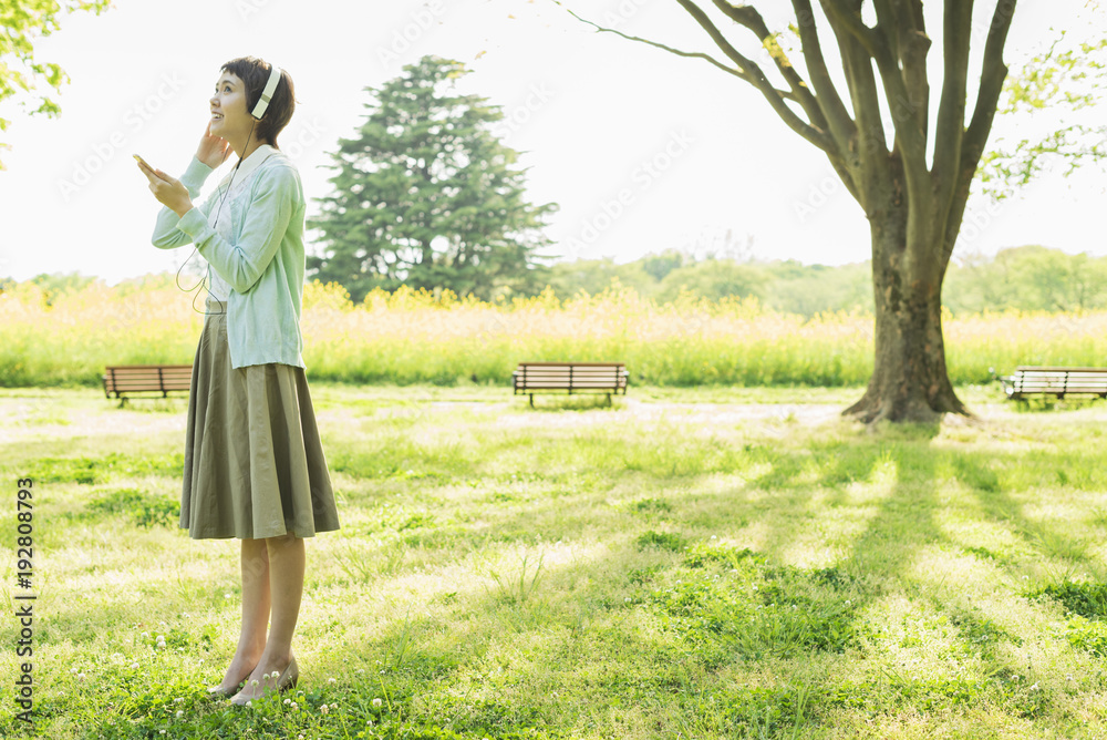 Naklejka premium 公園で音楽を聴く女性