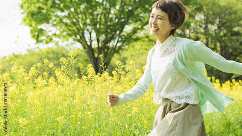 菜の花畑を散歩する女性