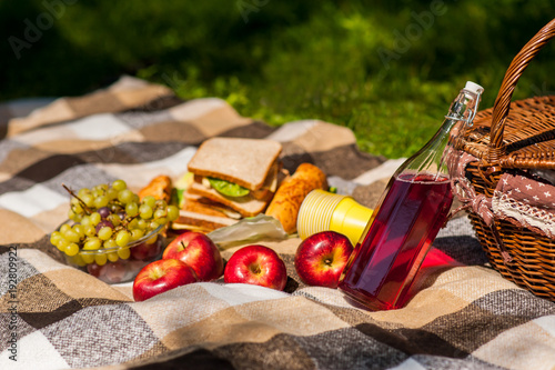 Picnic in nature. In the park or garden. Grapes apples sandwiches with wine or juice. Basket with food. Picnic Blanket.