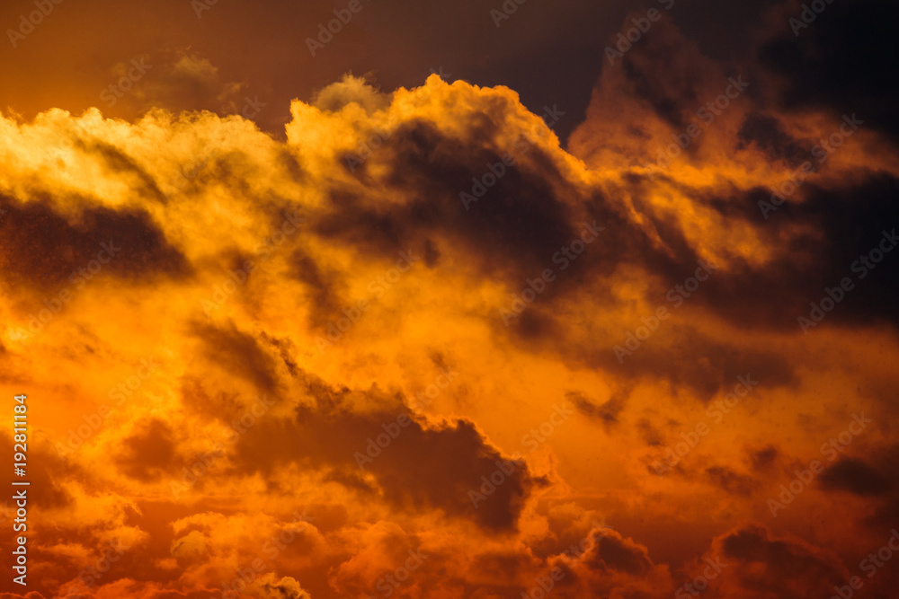 Fototapeta premium Dramatic view of a dark silhouettes of clouds in the orange sky illuminated by sunrise (background)