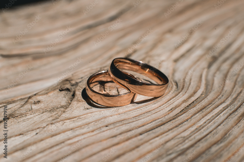 Pair of wedding golden rings on the yellow wooden rustic background Pair of wedding golden rings on the yellow wooden rustic background
