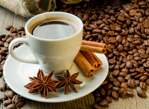 Coffee beans and coffee cup with cinnamon and anise on wooden board photo