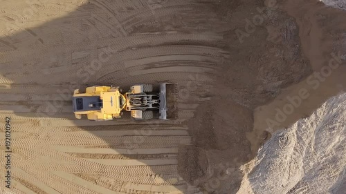 Aerial view loading bulldozer in open air quarry.