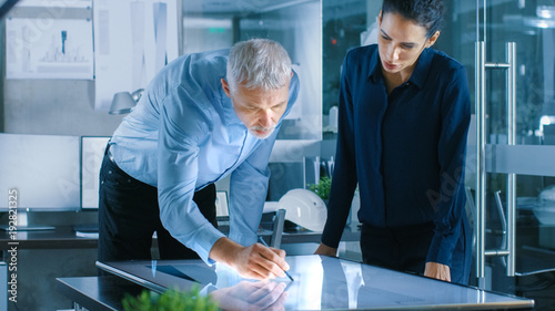 Senior Male and Young Female Architectural Designers Draw Building Concept on a GraphicsTablet Display Vertical Touchscreen Table. photo