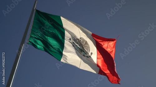 Angled slow motion of back lit Mexican flag waving in the wind. photo