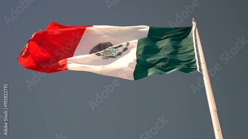 Pointing to the left large slow motion Mexican flag waving in the wind. photo