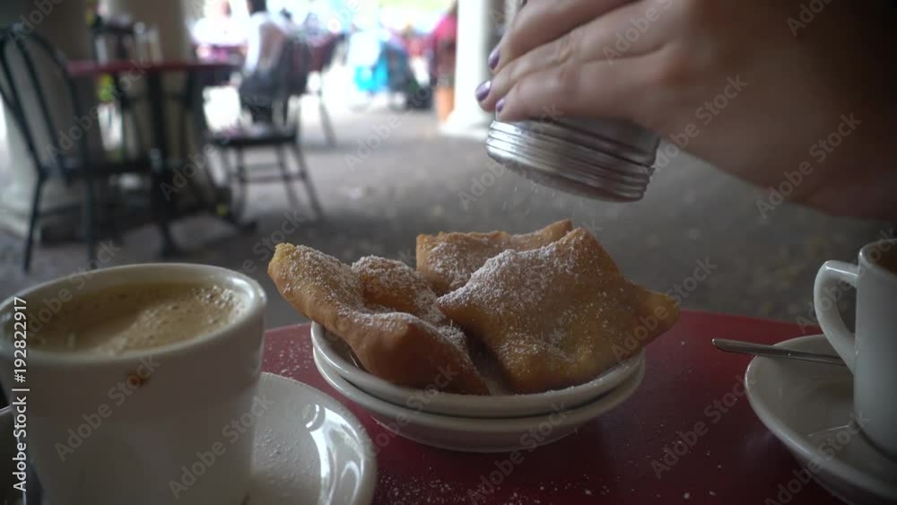 Adding powdered sugar to a beignet in New Orleans