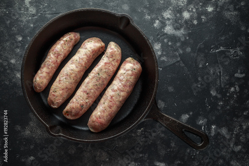 Freshly made raw breed butchers sausages in rustic skillet.