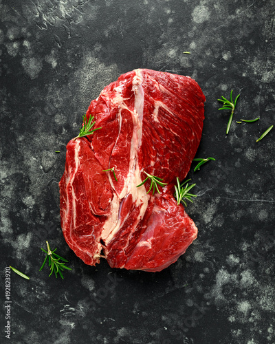 Fresh Raw braising steak on black background with rosemary
