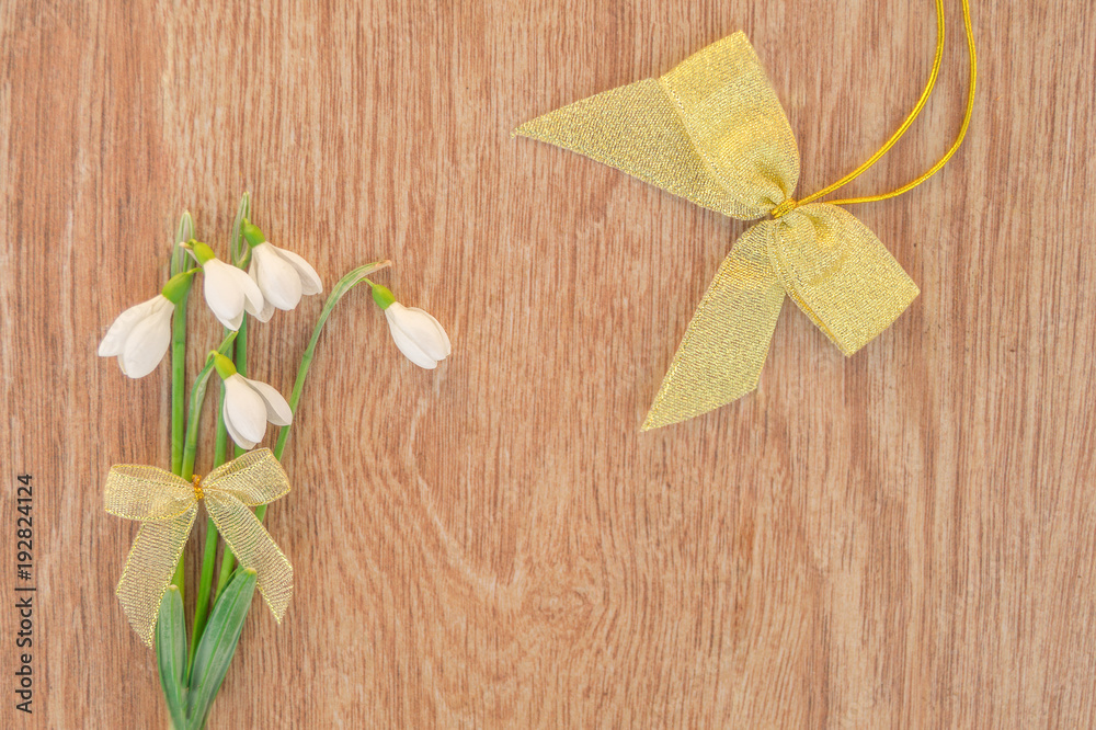 Bouquet of snowdrops with a bow on a wooden table