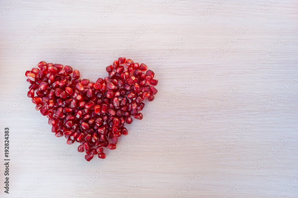 Heart made from grains of garnet on wooden table. Space for text Heart made from grains of garnet on wooden table. Space for text