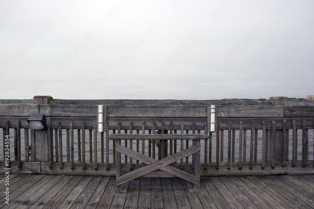 Folly Beach South Carolina, February 17, 2018 - empty bench on fishing pier with two fishing rod holders