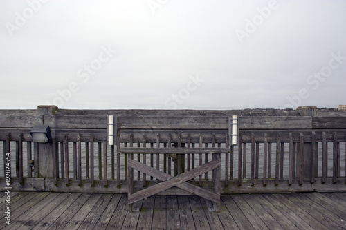 Folly Beach South Carolina, February 17, 2018 - empty bench on fishing pier with two fishing rod holders