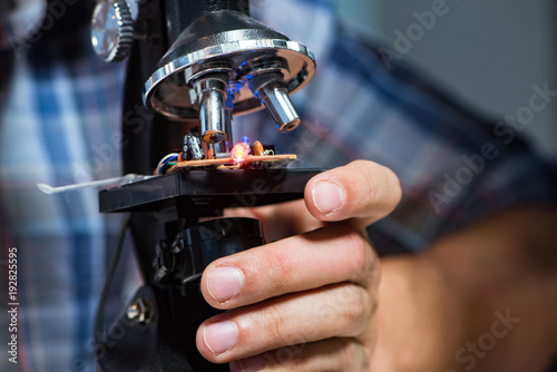 Repairman trying to repair laptop with miscroscope