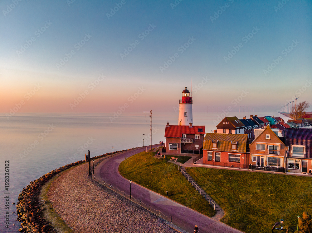 Sunset sky by the lighthouse of urk on the rocky beach at the lake Ijsselmeer by the former island Urk Flevoland Netherlands, Bird eye view drone view  - obrazy, fototapety, plakaty 