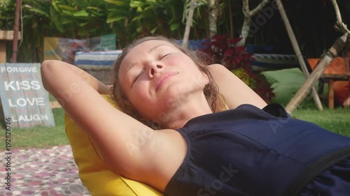 woman relaxes in a bag-chair on a clearing with green grass