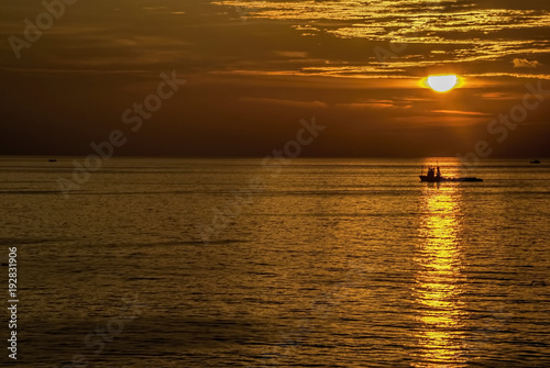 Golden hours in ocean with boat under sun light.