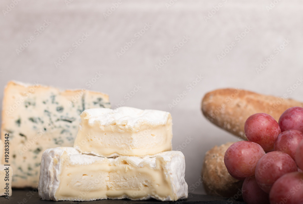 various french cheeses with red wina, grapes,baguette and nuts.