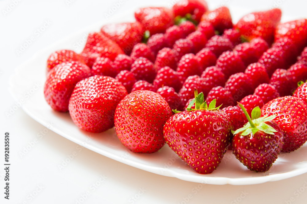 fresh raspberries and strawberries on a white plate fresh raspberries and strawberries on a white plate