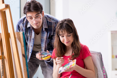 Artist coaching student in painting class in studio