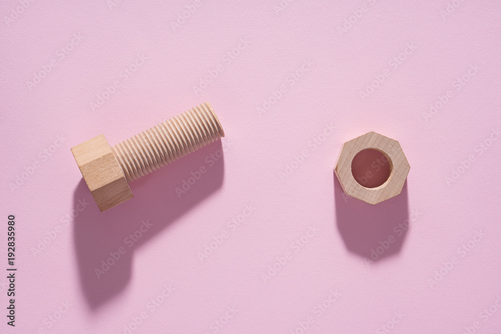 Hex nut and bolt on pink background. Build and repair concept, pop art. Wooden bolt and nut. Hex nut and bolt on pink background. Build and repair concept, pop art. Wooden bolt and nut.