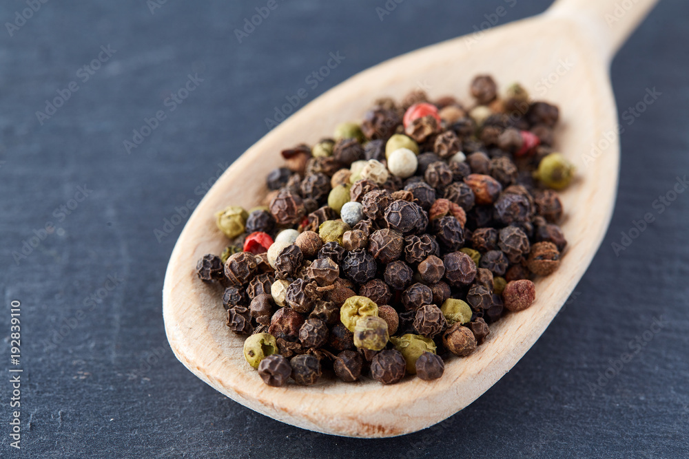 Top view of a wooden spoon full of allspice seeds isolated on dark background, shallow depth of field, front focus Top view of a wooden spoon full of allspice seeds isolated on dark background, shallow depth of field, front focus