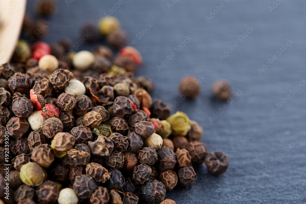 Obraz premium Top view of a wooden spoon full of allspice seeds isolated on dark background, shallow depth of field, front focus