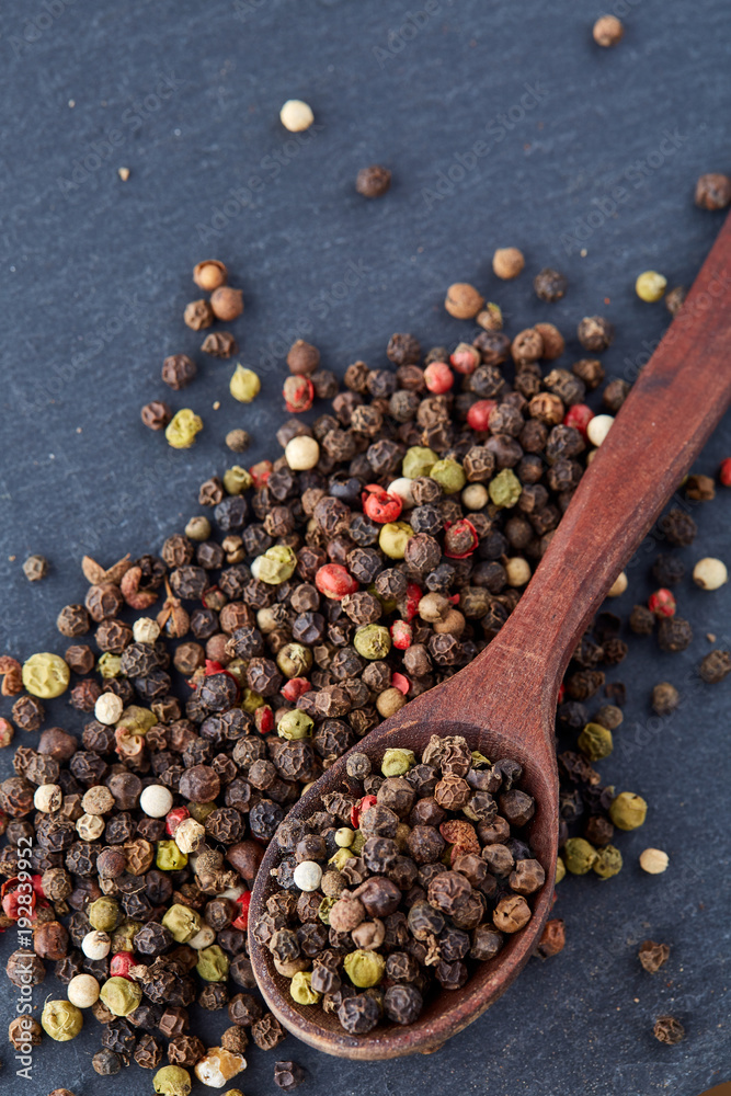 Top view of a wooden spoon full of allspice seeds isolated on dark background, shallow depth of field, front focus Top view of a wooden spoon full of allspice seeds isolated on dark background, shallow depth of field, front focus