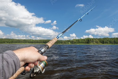 fishing rod in hand on the background of the shore, covered with