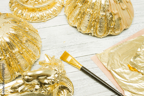 Gilding process. Gold leaf, brush and moldings on light table
