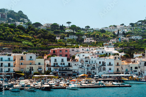 Italy stunning view of Capri when arriving to the island by ferry. Numerous boats and ferries at the dock. A lot of peole on the beach