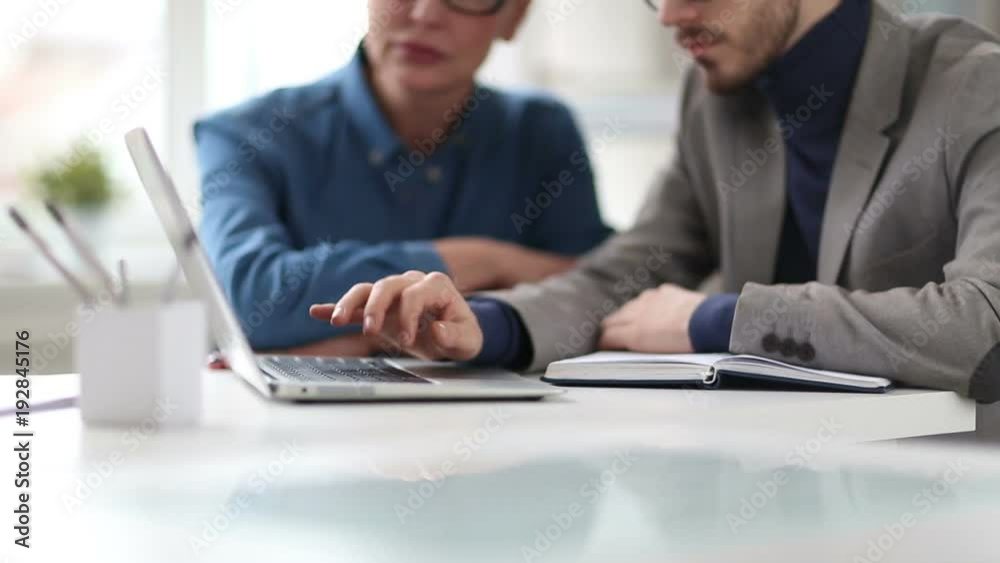 Cinemagraph of businessman typing on laptop keyboard while working with female colleague in office Cinemagraph of businessman typing on laptop keyboard while working with female colleague in office