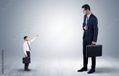 Small businessman pointing to a giant businessman