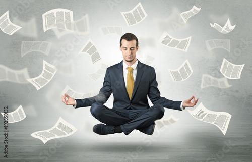 Businessman meditating with flying paper concept