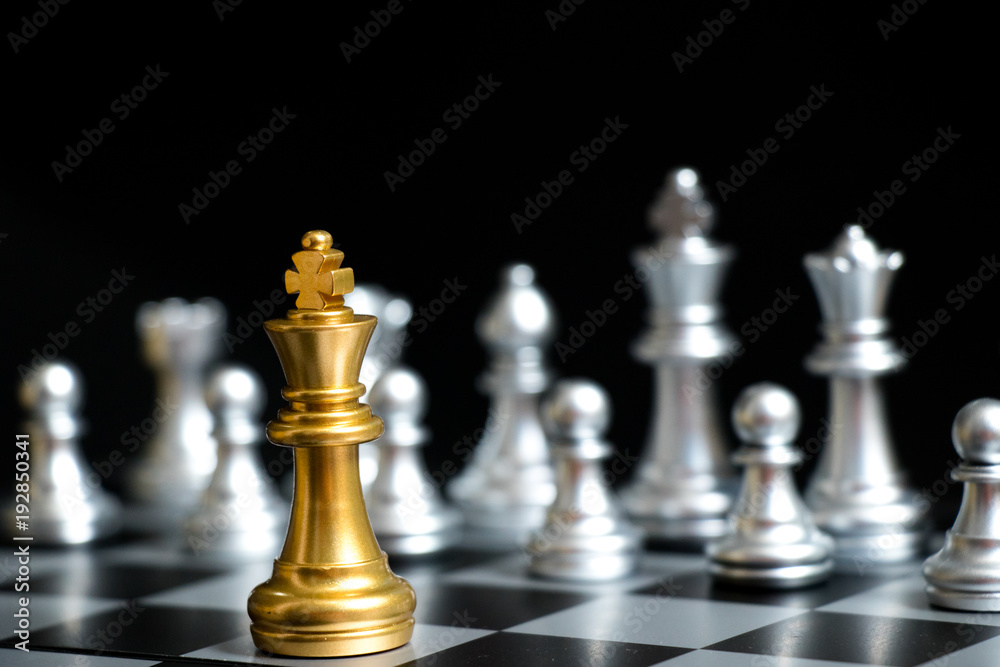 Gold King in chess game face with the another silver team on black background (Concept for company strategy, business victory or decision) Gold King in chess game face with the another silver team on black background (Concept for company strategy, business victory or decision)