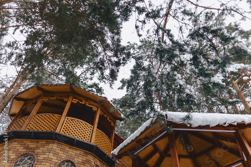 a wooden sauna and a cottage under the snow-covered pine trees photo