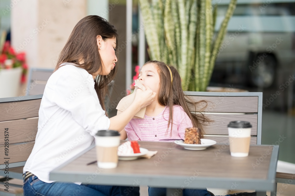 Mother wiping daughter's mouth at restaurant Mother wiping daughter's mouth at restaurant