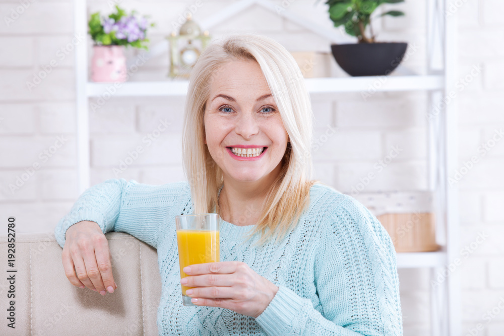 Woman drinking orange juice smiling. Beautiful middle aged Caucasian model face closeup. Woman drinking orange juice smiling. Beautiful middle aged Caucasian model face closeup.