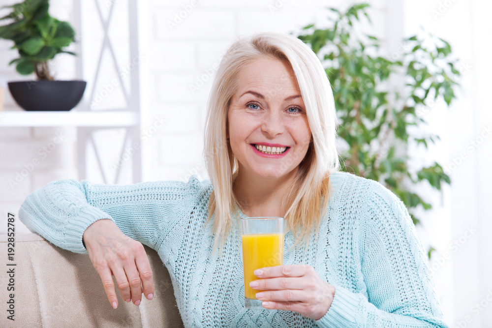 Woman drinking orange juice smiling. Beautiful middle aged Caucasian model face closeup. Woman drinking orange juice smiling. Beautiful middle aged Caucasian model face closeup.