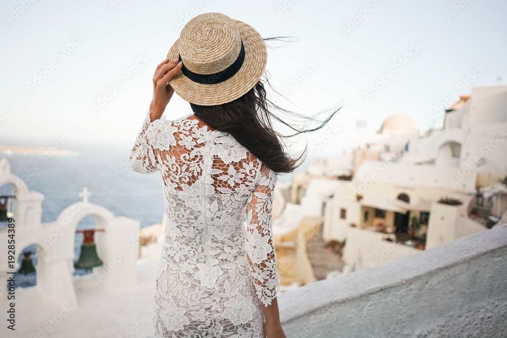 Woman in white dress and straw hat on Santorini island