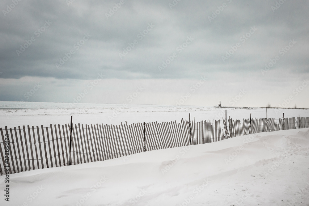 Wooden fence running down snowy beach