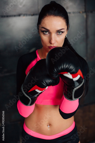 Close up portrait of a young sportswoman in boxing gloves. Pretty female brunete boxer. Healthy lifestyle concept. Girl fighter.