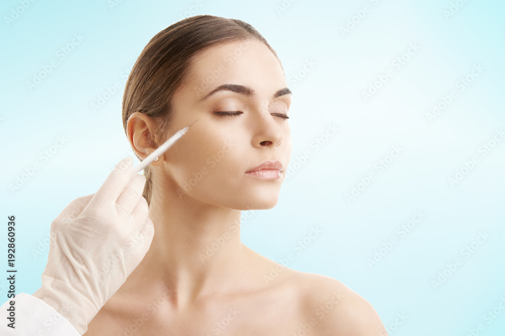 Young woman receiving cosmetic injection with syringe Young woman receiving cosmetic injection with syringe