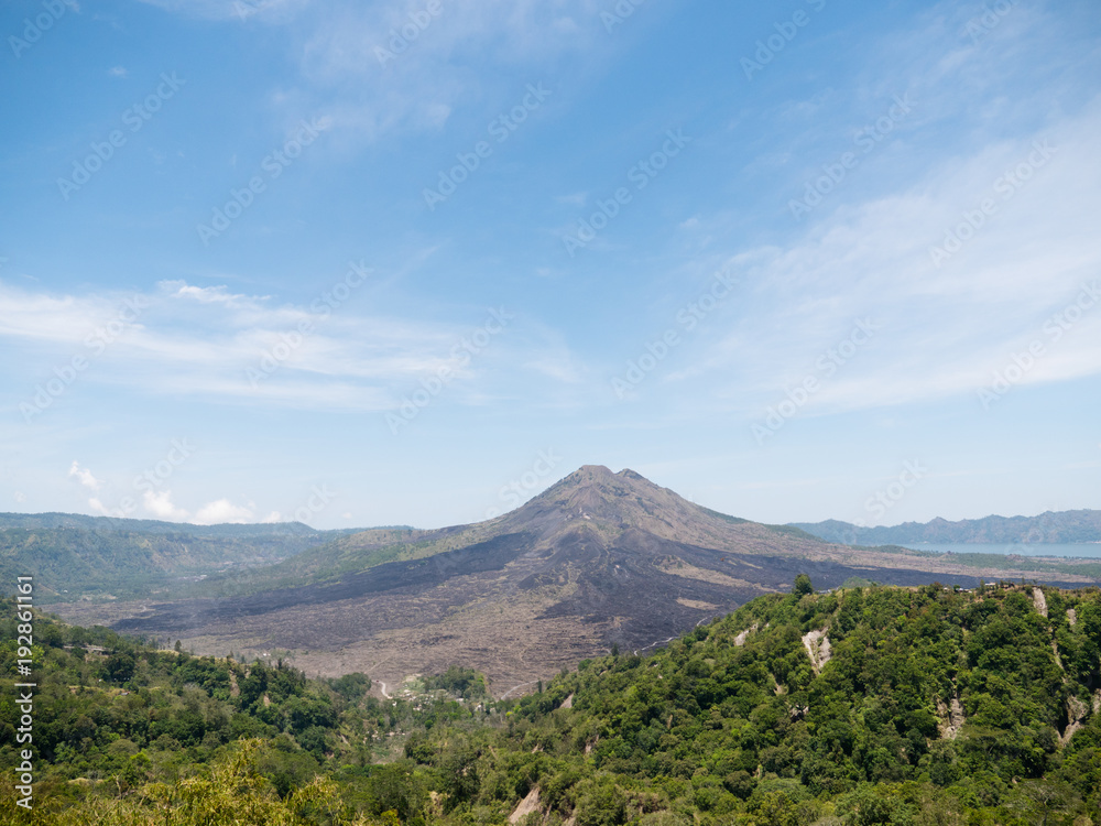 Volcano, mountain covered forest, sky with clouds, traces of lava on the ground. Mount Batur Volcano in Kintamani. Mountain landscape, Bali. Travel concept.
