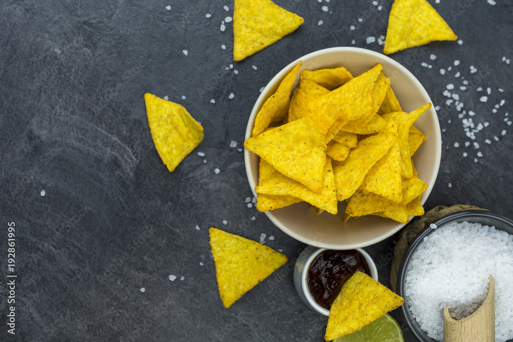 Tortilla chips with barbecue dip on a black stone table. Tortilla chips with barbecue dip on a black stone table.