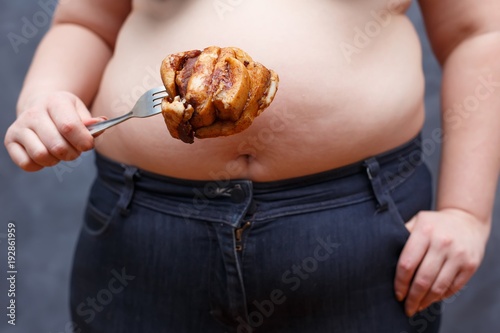 Weight loss, junk food, overweight, dieting, food addiction concept. Unknown woman holding a fork with big piece of bacon