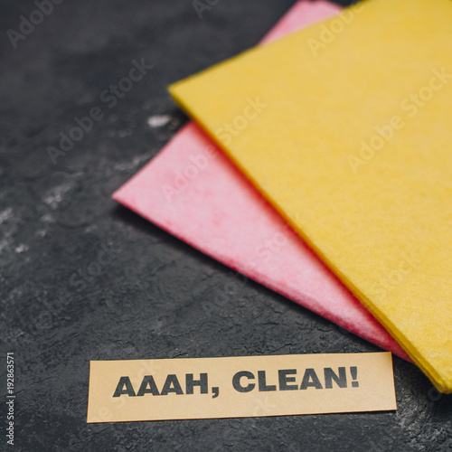 Cleaning house or office concept. Red and yellow cleaning rags, AAAH, CLEAN inscription on a dark concrete background. Top view, closeup photo